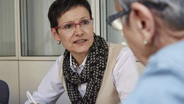 Seniorin mit schwarzem Kurzhaarschnitt ber&auml;t eine Seniorin in der Sozialberatung